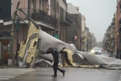 Un hombre pasa por una sección del techo que se desprendió de un edificio en el Barrio Francés por los vientos del huracán Ida, el domingo 29 de agosto de 2021, en Nueva Orleans.