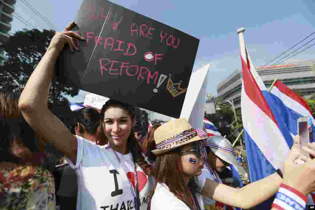 A Thai anti-government protester holds a banner as she joins a rally outside Prime Minister Yingluck Shinawatra's residence, Dec. 22, 2013, Bangkok, Thailand.