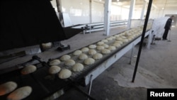 FILE - A man sweeps the floor near bread at a bakery in Azaz, Syria, Jan. 26, 2020.
