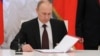 Russian President Vladimir Putin prepares to sign a law on ratification of a treaty making Crimea part of Russia, during a ceremony in Moscow's Kremlin in Moscow, March 21, 2014. 