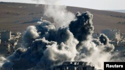 Sebuah ledakan akibat serangan udara tampak di tengah kota Kobani, 9 November 2014. Foto diambil dari negara Turki di perbatasan Turki dan Suriah.