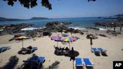 FILE - Tourists spend time on Patong Beach in Phuket province, southern Thailand. Thailand’s sapphire blue waters, wildlife parks, delicious cuisine and raunchy red light districts have attracted tourists for decades, March 13, 2014.
