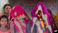 FILE - An underage bride, right, stands with family members during her marriage at a Hindu temple near Rajgarh, Madhya Pradesh state, India, April 17, 2017.