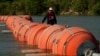 Una persona en kayak pasa al lado de boyas instaladas como barrera en el Río Grande, el 1 de agosto de 2023, en Eagle Pass, Texas, EEUU.
