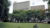 FILE - Zimbabweans rest at a park outside Meikles Hotel in central in Harare, February 24, 2015.
