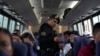 Un agente de policía revisa las identificaciones de los pasajeros de autobús en un punto de control de contrabando en Pucusana, Perú, el lunes 17 de julio de 2023. 
