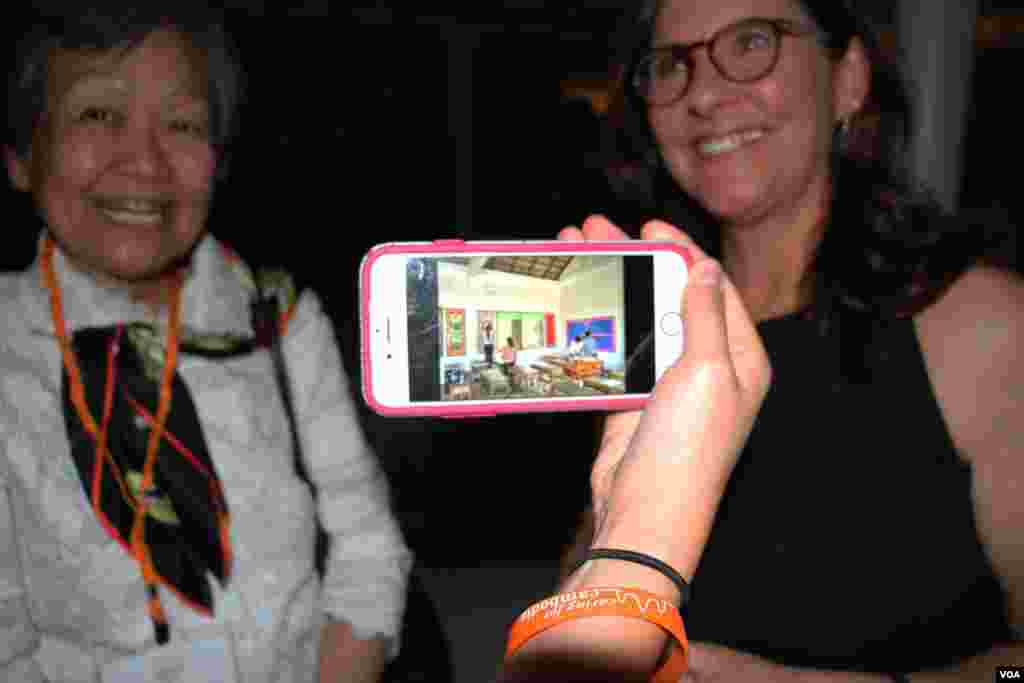 A guest shows photos of a partnering school of Caring for Cambodia at a Washington, DC fundraiser and silent auction organized by the non-profit to help support 21 impoverished schools in Cambodia's Siem Reap province, May 4, 2017. (VOA Khmer) 