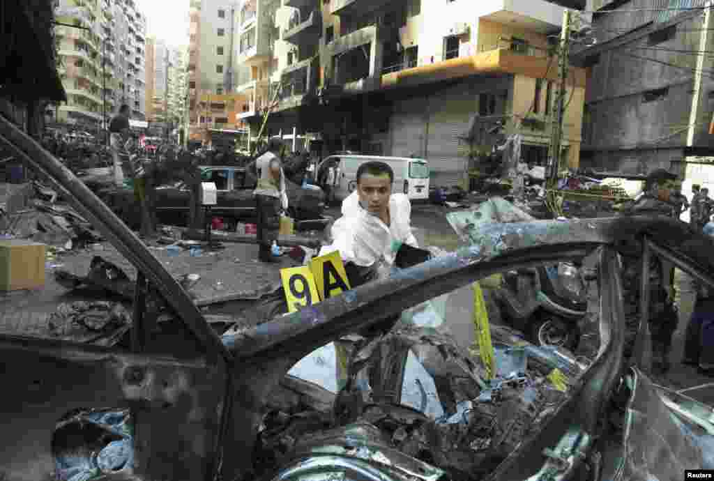 A forensic inspector examines a vehicle at the site of a car bomb in Beirut's southern suburbs, August 16, 2013.