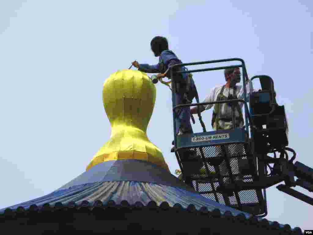 Workers touch up repairs to wind damage on the golden silk roof of the three-story tall Heavenly Temple. (A. Chimes/VOA)
