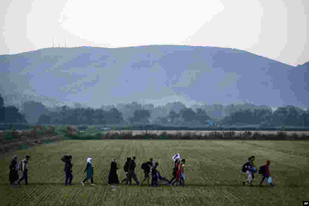 Para migran mendekati pos pemeriksaan perbatasan di kota Idomeni, Yunani, dan menyeberangi Makedonia selatan (3/9). Makedonia telah menanggung arus masif pengungsi dan migrasi orang-orang yang menuju Uni Eropa, dengan lebih dari 200.000 orang tiba di sana sejauh ini tahun ini. (AP/Giannis Papanikos)