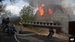 Petugas pemadam kebakaran berusaha memadamkan rumah yang terbakar akibat serangan artileri di Donetsk, Ukraina timur Minggu (5/10).