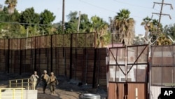 FILE - Marines patrol during work to fortify the border structure that separates Tijuana, Mexico, behind, and San Diego, near the San Ysidro Port of Entry, Nov. 9, 2018, in San Diego.