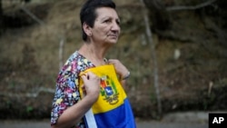 Una mujer que sostiene una bandera nacional venezolana asiste a una manifestación política en el interior del país. 17 de abril de 2024