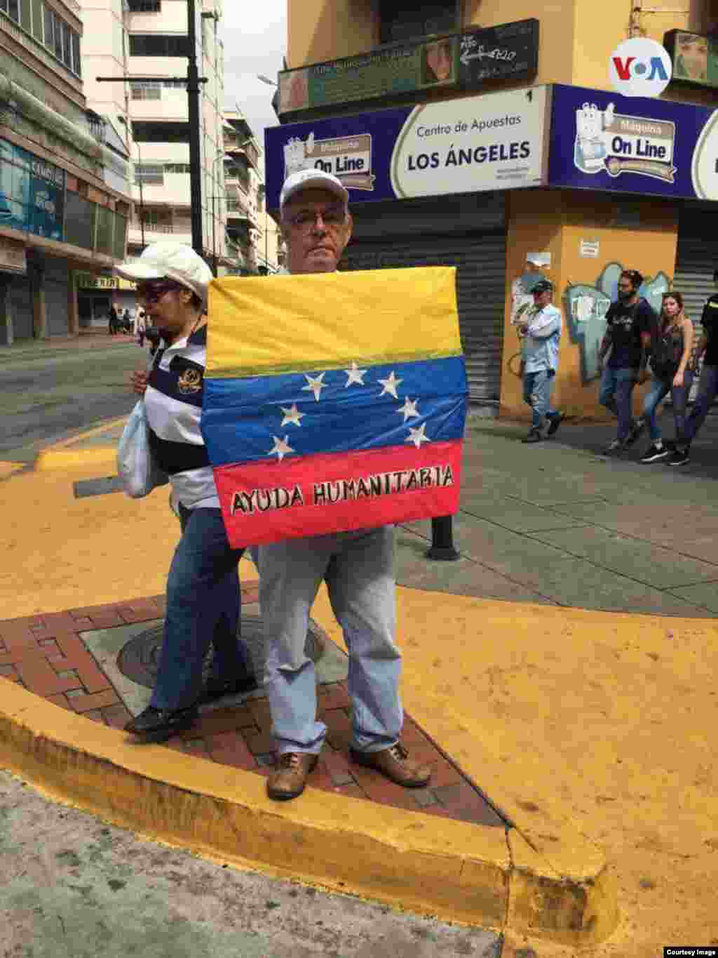 Un hombre venezolano carga la bandera de Venezuela durante protesta en Caracas. 