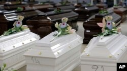 FILE - Teddy bears and flowers placed are placed on the coffins of deceased migrants inside a hangar at Lampedusa's airport, Italy, Saturday, Oct. 5, 2013.
