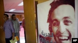Journalists walk past a poster showing jailed Egyptian photojournalist Mahmoud Abou-Zeid, known by his nickname Shawkan at the press syndicate in Cairo, Egypt, Aug. 12, 2015. He's been locked up without any charges for covering the Rabaa massacre in Cairo, when police and army officers shot and killed hundreds of protesters on Aug. 14, 2013.