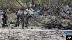 Somali soldiers attend the scene where a suicide car bomber detonated near the gates of the motor vehicle imports duty authority headquarters near the port in Mogadishu, Somalia, July 4, 2020. 