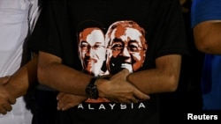 Seorang pendukung mengenakan kaus bergambar politisi Anwar Ibrahim dan Perdana Menteri Mahathir Mohamad saat kampanye di Kuala Lumpur, Malaysia, 16 Mei 2018.