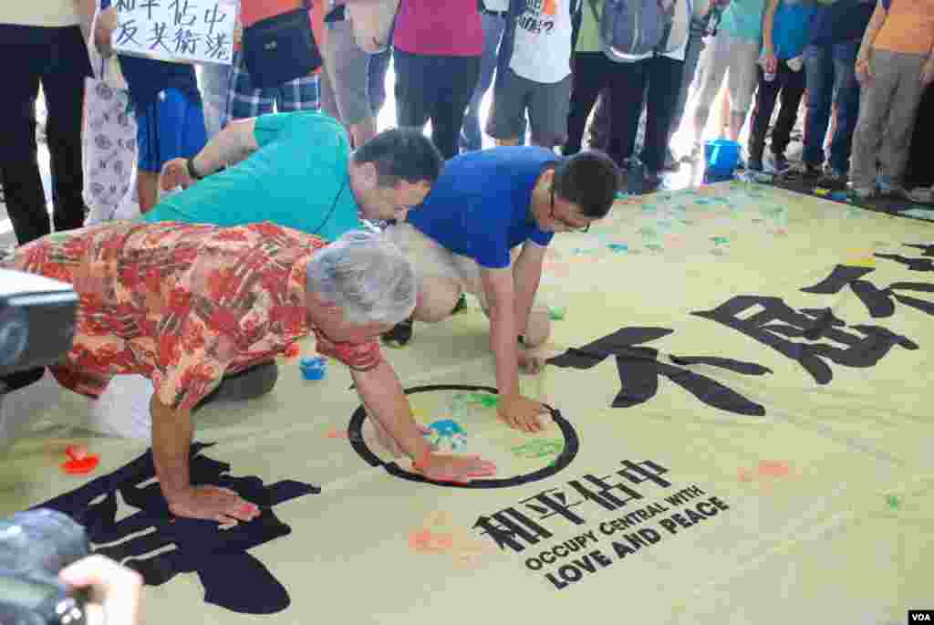佔中三位發起人在印有「和平抗爭、不屈不撓」的橫額上打手印,表達和平抗爭的決心(美國之音湯惠芸拍攝)
