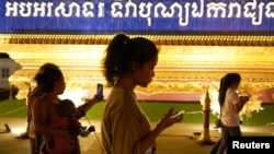 FILE - People walk using their mobiles phones in Phnom Penh, Cambodia, Feb. 18, 2021. The Cambodian government issued a sub-decree to establish a National Internet Gateway that would give it control over the flow of information on the internet.