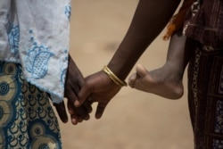 Pengungsi Nigeria berusia lima belas tahun, Fati, berjalan bersama ibunya, Mariam, sambil menggendong adiknya di kamp pengungsi Minawao, Kamerun Utara, 5 April 2016. (Karel Prinsloo/UNICEF/Handout via REUTERS)