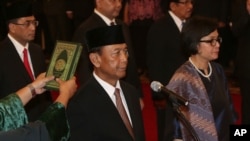 Indonesia's newly appointed Coordinating Minister for Legal, Politics and Security Affairs Wiranto, left, and Finance Minister Sri Mulyani Indrawati, right, are sworn in during the inauguration ceremony for the new cabinet members at the State Palace in Jakarta, July 27, 2016. 