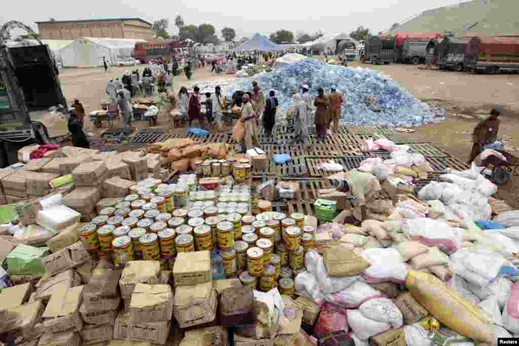Des travailleurs remplissent des brouettes de l'aide pour les déplacés à l'intérieur d'un centre de distribution alimentaire dans un stade à Bannu, dans le nord-Pakistan, le 25 Juillet 2014.