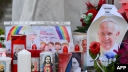 Velas, flores y un retrato del papa Francisco se colocan en la estatua de Juan Pablo II afuera del hospital Gemelli, donde está hospitalizado el Papa Francisco, en Roma, el 24 de febrero de 2025.