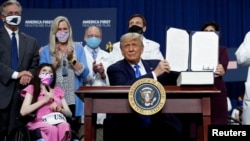 President Donald Trump displays an executive order he signed at a campaign event on health care at Charlotte Douglas International Airport in Charlotte, N.C., Sept. 24, 2020.
