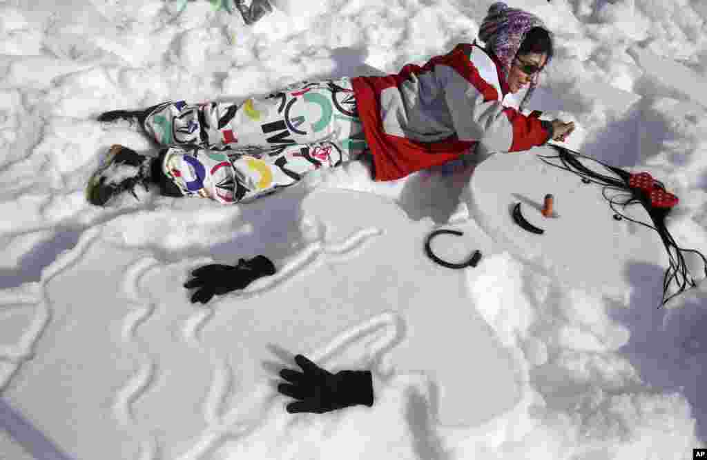 An Iranian woman makes a snowwoman in a competition in Dizin north of the capital Tehran, Iran. Some 600 Iranians participated in a snow festival organized by Iran's ski federation at the Dizin ski resort.