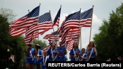 Des gens portent des drapeaux américains pendant qu'ils participent à un défilé lors des célébrations de la fête de l'indépendance du 4 juillet à Washington, D.C., États-Unis, le 4 juillet 2019. REUTERS / Carlos Barria