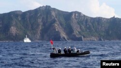 Sebuah perahu Penjaga Pantai Jepang (depan) dan kapal layar berisi sekitar 20 aktivis nasionalis dan nelayan Jepang berlayar ke kepulauan sengketa Senkaku di Timur Laut Cina (18/8).