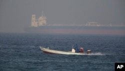 Sebuah kapal nelayan berlayar melintas sebuah tanker minyak di kejauhan di Fujaira, Uni Emirat Arab, 15 Juni 2019. 