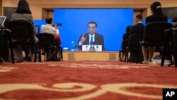 Chinese Premier Li Keqiang speaks on screen during a press conference by video conferencing at the end of the National People's Congress in Beijing on Thursday, May 28, 2020. 