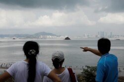 FILE- A tourist points at China's Xiamen from a former military fort on Lieyu island in Kinmen county, Taiwan, Aug. 20, 2018.
