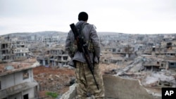Seorang penembak jitu Suriah Kurdi mengamati reruntuhan kota Kobani (Foto: dok).