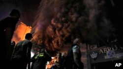 Firefighters and rescuers gather outside a computer shop hit in an Israeli airstrike in central Beirut, Nov. 17, 2024.
