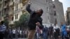 A protester throws stones at riot police during clashes at Tahrir square in Cairo, November 26, 2012.