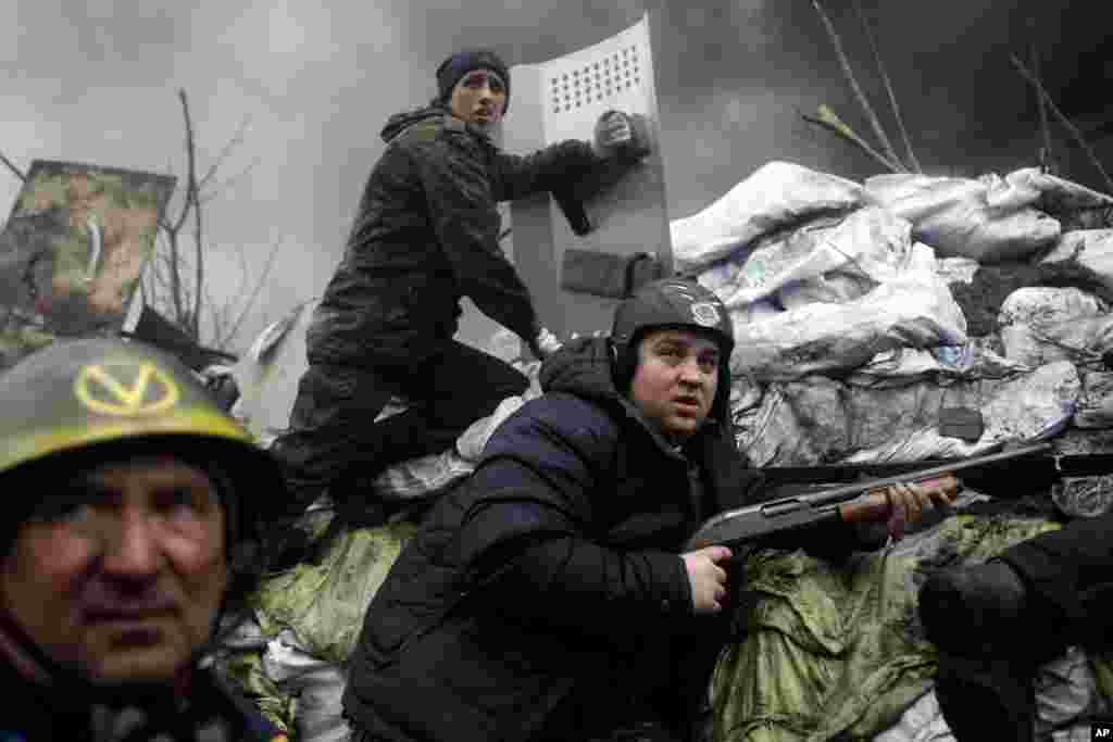 An anti-government protester holds a firearm as he mans a barricade on the outskirts of Independence Square, Kyiv, Feb. 20, 2014. 