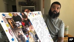 Roland Mack holds a poster with pictures and messages made by family members in memory of his sister, Chantee Mack, in District Heights, Md., whose family and co-workers believe, she and several colleagues contracted the disease in their office.