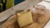 A cheese maker cuts a slice of cheese 