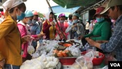 Garment factory workers wear face masks as they buy food on a lunch break near Propitious (Cambodia) Garment Ltd factory, in Kandal province, Cambodia, March 20, 2020. (Kann Vicheika/VOA Khmer) 
