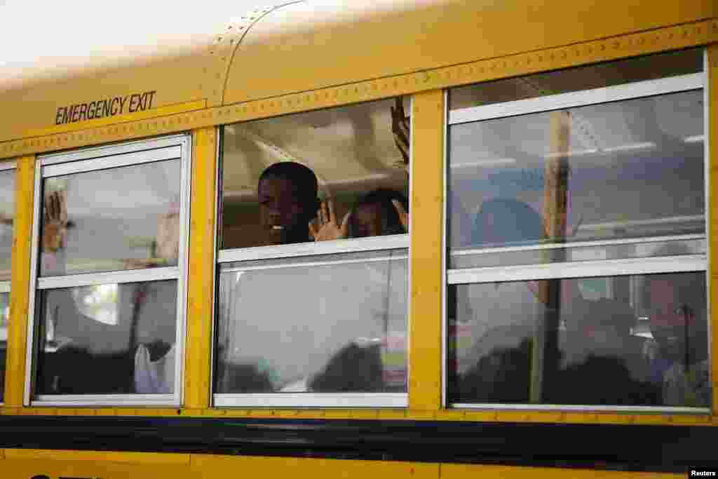 Sebuah bus sekolah dipenuhi anak-anak yang berseru "Tangan di atas, jangan tembak" saat kendaraan tersebut melewati tempat di mana polisi St. Louis Metropolitan sebelumnya menembak seorang pria bersenjata pisau sampai tewas di St. Louis (19/8). (Reuters/Lucas Jackson)