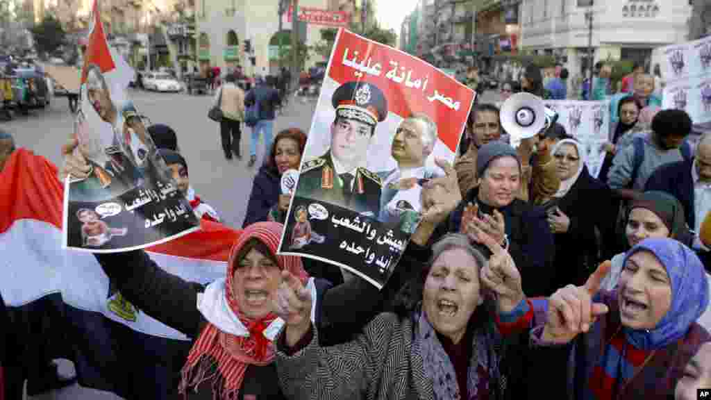 Activists shout anti-terrorism slogans as they hold posters with Arabic slogans that read, "Egypt is entrusted to us. The army and people are one hand," during a rally in Cairo, Dec. 26, 2013.