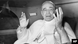 FILE - Pope Pius XII smiles as he waves with both arms, sitting in his car, in response to the cheers from a crowd gathered outside the papal summer residence, Nov. 29, 1955.