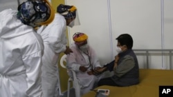 Un médico revisa los signos vitales de una anciana luego de ser inoculada con una dosis de la vacuna Pfizer COVID-19 como parte del período de observación, en el centro de convenciones convertido en sitio de vacunación, en Quito, Ecuador, el 31 de marzo. 