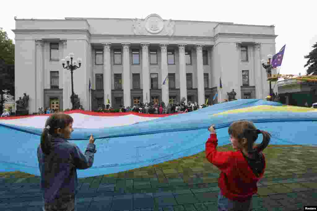 People hold a combined Ukrainian-Crimean flag during a pro-Ukrainian rally in front of the parliament building in Kyiv, June 5, 2014.