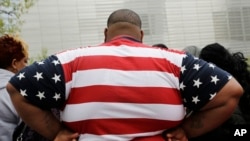 FILE - In this Thursday, May 8, 2014 photo, an overweight man wears a shirt patterned after the American flag during a visit to the World Trade Center, in New York. 