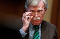FILE - National Security Adviser John Bolton adjusts his glasses as U.S. President Donald Trump speaks in the Oval Office at the White House in Washington, April 2, 2019.