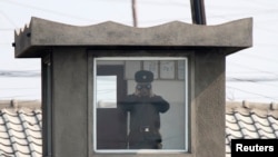 북한 접경도시 신의주의 국경 초소에서 북한 병사가 망원경으로 중국 쪽을 바라보고 있다. 압록강 너머 중국 단둥에서 촬영한 사진이다.